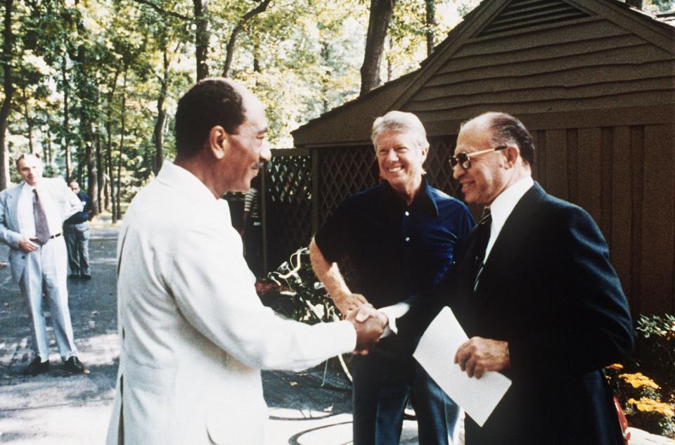 This file photo shows former Egyptian President Anwar al-Sadat (L) as he shakes hands with former Israeli Premier Menachem Begin, as former US President Jimmy Carter looks on, Swept. 6, 1978 at Camp David, the US presidential retreat in Maryland. Egypt began peace initiatives with Israel in late 1977, when Sadat visited Jerusalem. A year later, with the help of Carter, terms of peace between Egypt and Israel were negotiated at Camp David. A formal treaty, signed 26 March 1979 in Washington, DC, granted full recognition of Israel by Egypt, opened trade relations between the two countries, and limited Egyptian military buildup in the Sinai. Israel agreed to return a final portion of occupied Sinai to Egypt.