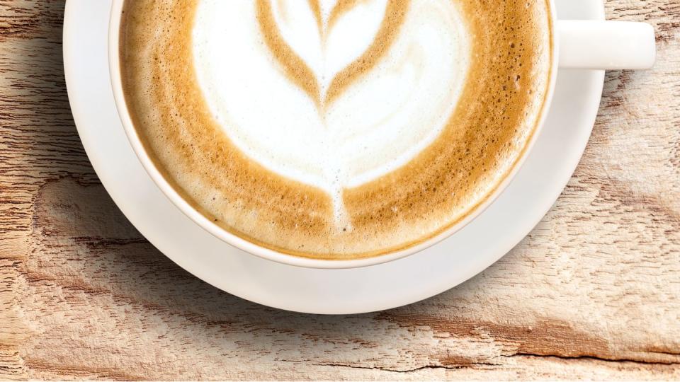 latte in a white mug on a wooden table