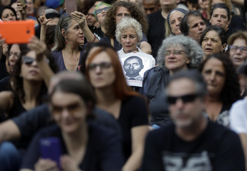 A woman holds a photo of a person who was killed during Brazil's dictatorship during a protest in Sao Paulo, Brazil, Sunday, March 31, 2019. Over the objections of human rights groups, but with the support of far-right President Jair Bolsonaro, some military bases are commemorating the March 31, 1964, coup that lasted two decades in Brazil and made for thousands of victims. (AP Photo/Andre Penner)