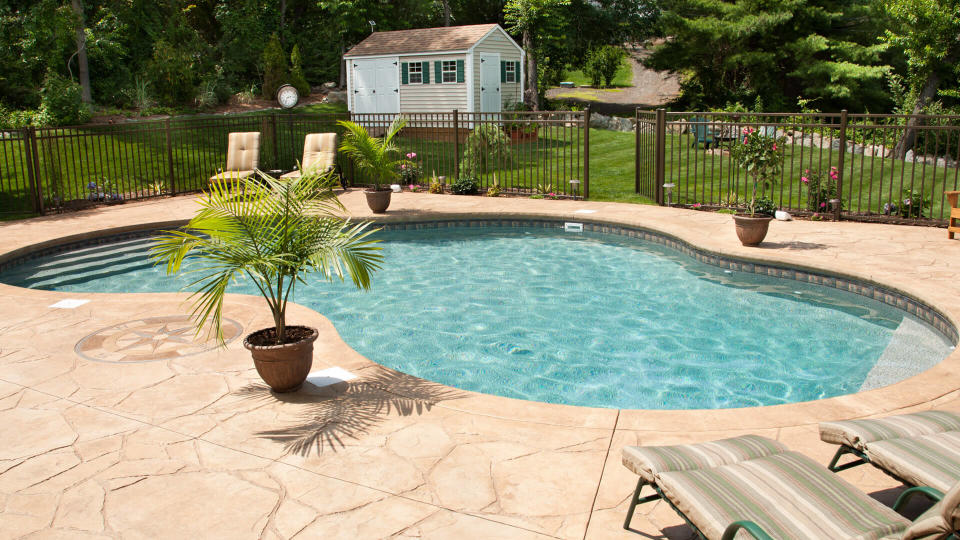 "Lush, resort-like backyard salt water swimming pool with flagstone stamped concrete patio.