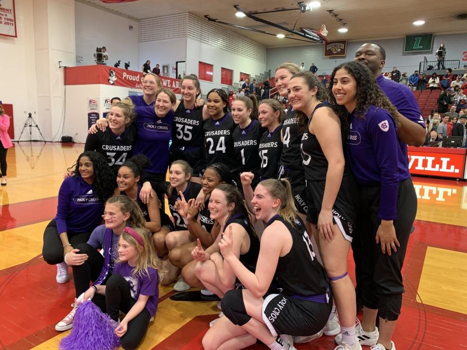 Players and coaches of the Holy Cross women's basketball team pose after the Crusaders upended Boston University for the Patriot League championship and NCAA Tournament bid.