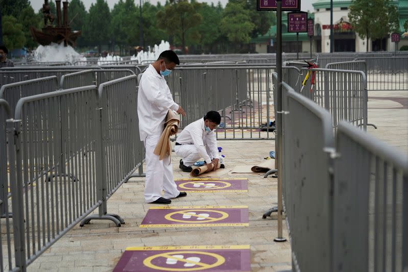 Workers wearing face masks prepare social distancing markers at Shanghai Disney Resort