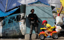 <p>A boy on a cart is pushed near a Brazilian Public-Safety National Force policeman as he patrols an entrance of Chapadao slums complex during a security operation on an effort to crack down on crime in Rio de Janeiro, Brazil, May 15, 2017. (Photo: Ricardo Moraes/Reuters) </p>