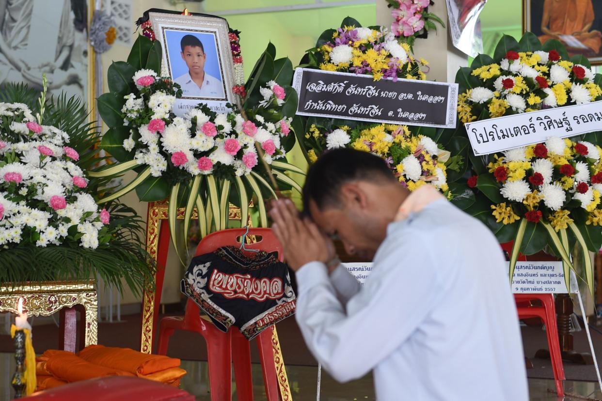 A mourner prays in front of a portrait of 13-year-old Anucha Tasako next to his coffin during his funeral at a Buddhist temple in the Samut Prakan province of Thailand on Wednesday: Romeo Gacad/AFP/Getty Images