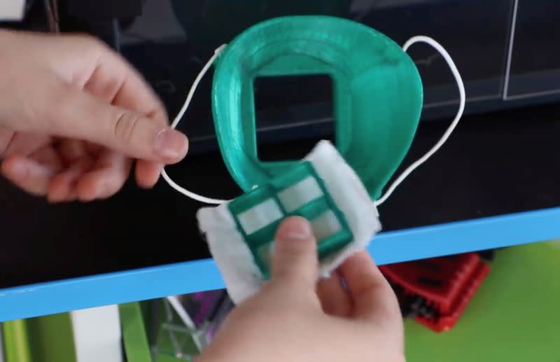 A high school student demonstrates a protective mask holder that he has been 3D-printing for healthcare workers in Trinity, Florida