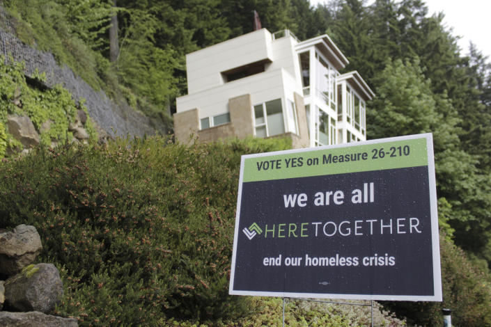 FILE - A campaign sign urging people to vote "Yes" on Measure 26-210, which would approve taxes on personal income and business profits to raise $2.5 billion over a decade to fight homelessness, is displayed near an upscale home in Portland, Ore., on May 14, 2020. Oregon's reputation for political harmony is being tested as a Republican walkout in the state Senate continues for a third week. The boycott could derail hundreds of bills and approval of a biennial state budget, as Republicans and Democrats refuse to budge on their conflicting positions over issues including abortion rights, transgender health and guns. (AP Photo/Gillian Flaccus, File)