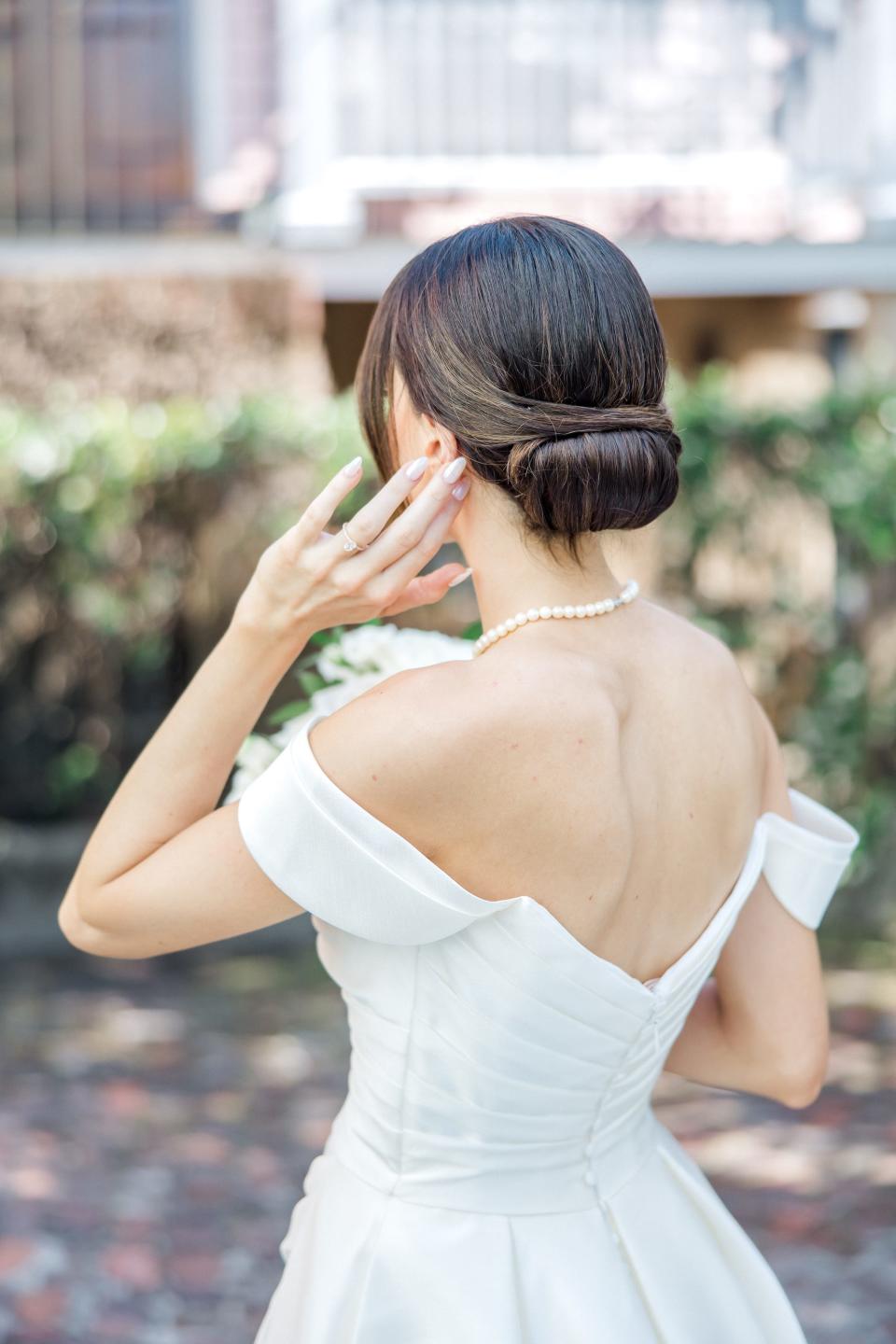 A bride adjusts her hair as she looks away from the camera.