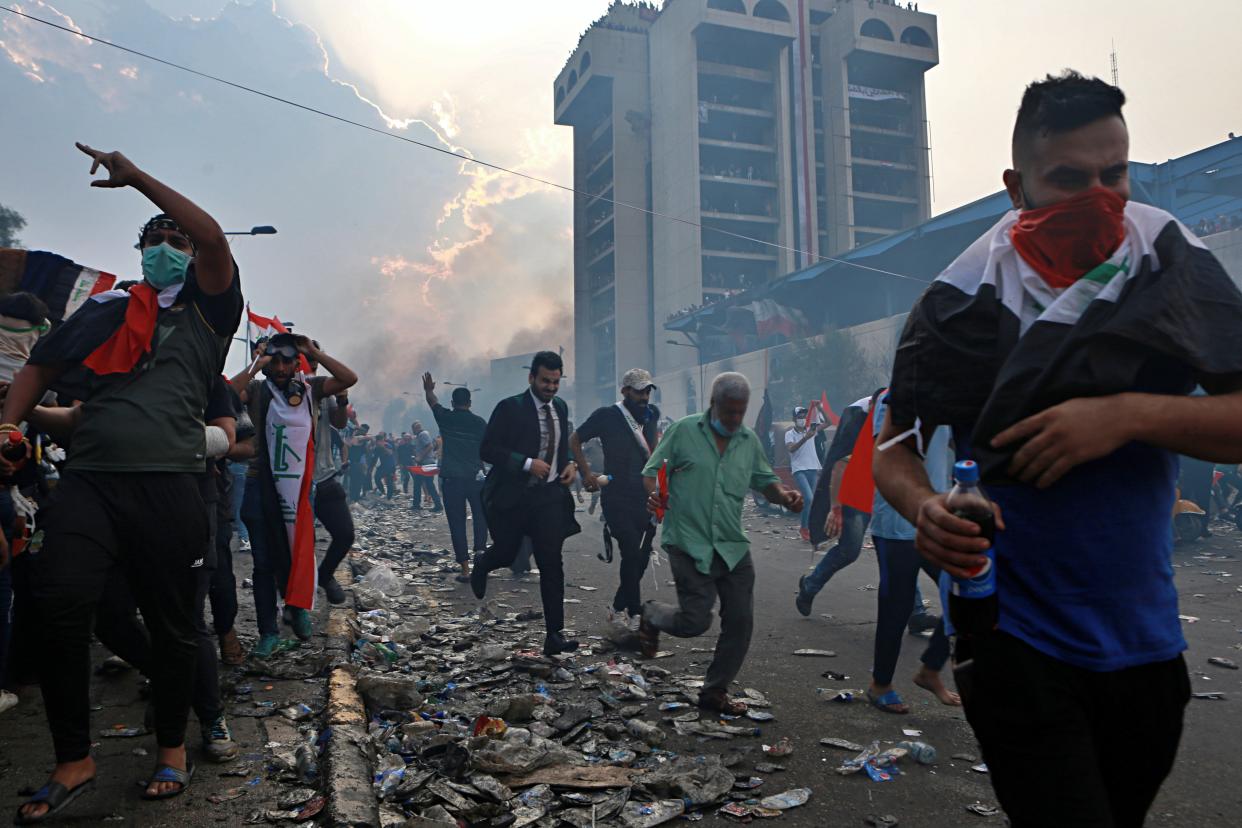 Anti-government protesters run to take cover while Iraqi Security forces fire tear gas during a demonstration in Tahrir Square in Baghdad, Iraq, Monday, Oct. 28, 2019. (Photo: Khalid Mohammed/AP)