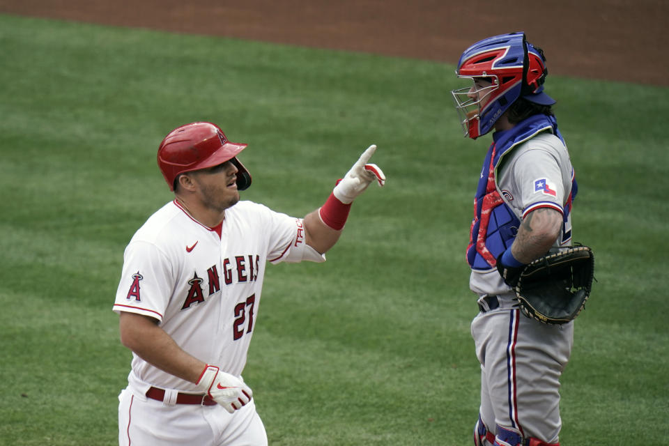 Los Angeles Angels' Mike Trout, left, celebrates his home run as Texas Rangers catcher Jonah Heim looks away during the first inning of a baseball game, Wednesday, April 21, 2021, in Anaheim, Calif. (AP Photo/Jae C. Hong)