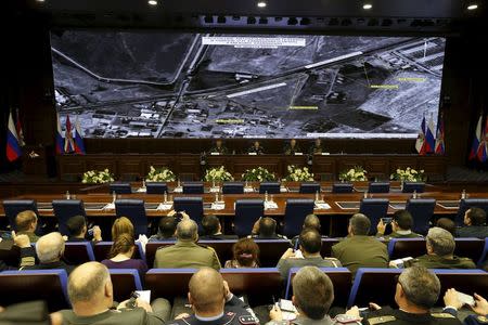 Defence ministry officials sit under screens with satellite images on display during a briefing in Moscow, Russia, December 2, 2015. REUTERS/Sergei Karpukhin