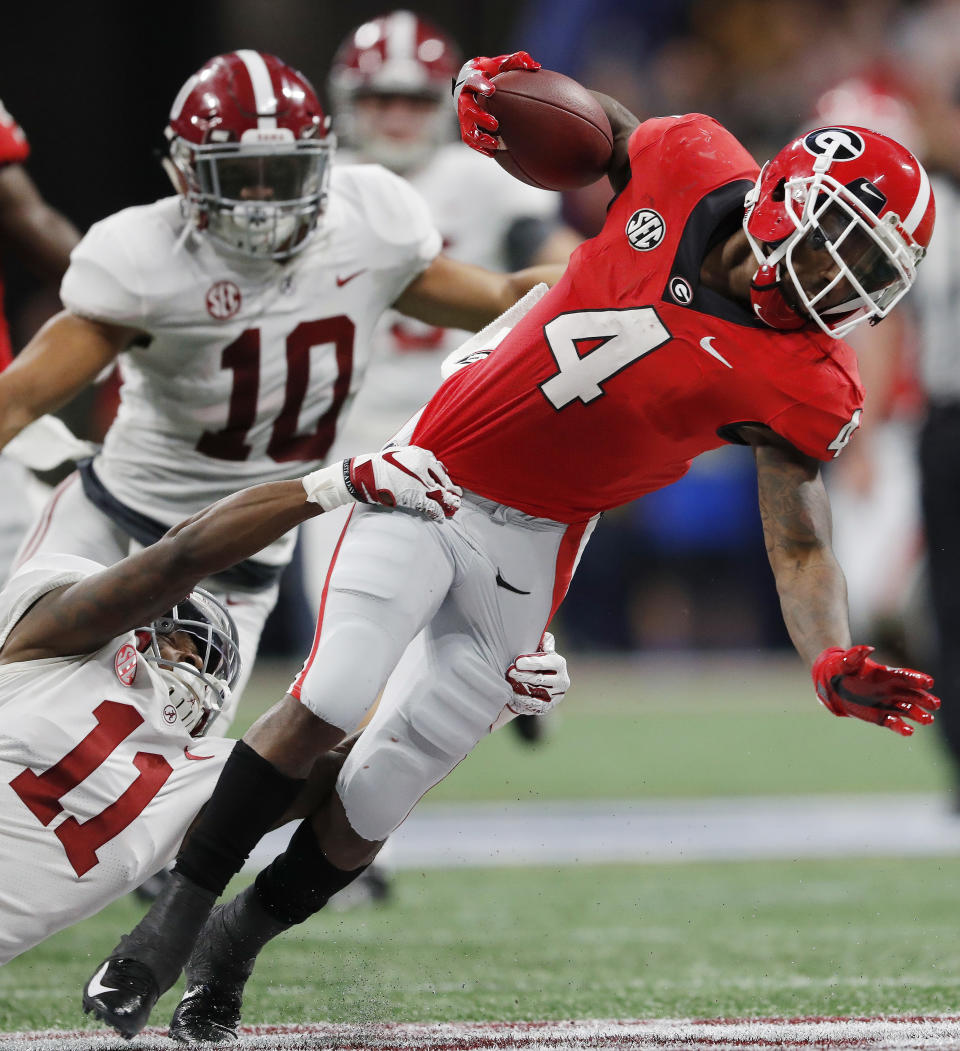 Alabama's Henry Ruggs III (11) tackles Georgia wide receiver Mecole Hardman (4) on a punt return during the second half of the Southeastern Conference championship NCAA college football game, Saturday, Dec. 1, 2018, in Atlanta. (AP Photo/John Bazemore)