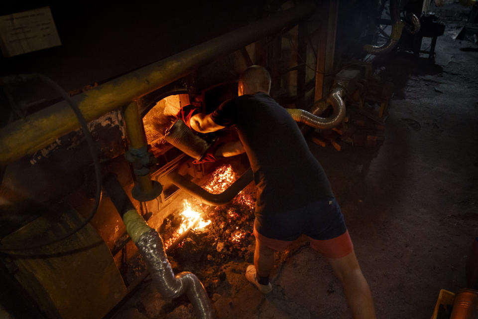 Nikita, one of three men working a 12-hour night shift, loads coal into a boiler at a bakery in Kostiantynivka, Donetsk region, eastern Ukraine, Monday, Aug. 15, 2022. Since the bakery lost its gas supply, it was reconfigured to run on coal, a system which hadn't been used at this plant since World War II. (AP Photo/David Goldman)