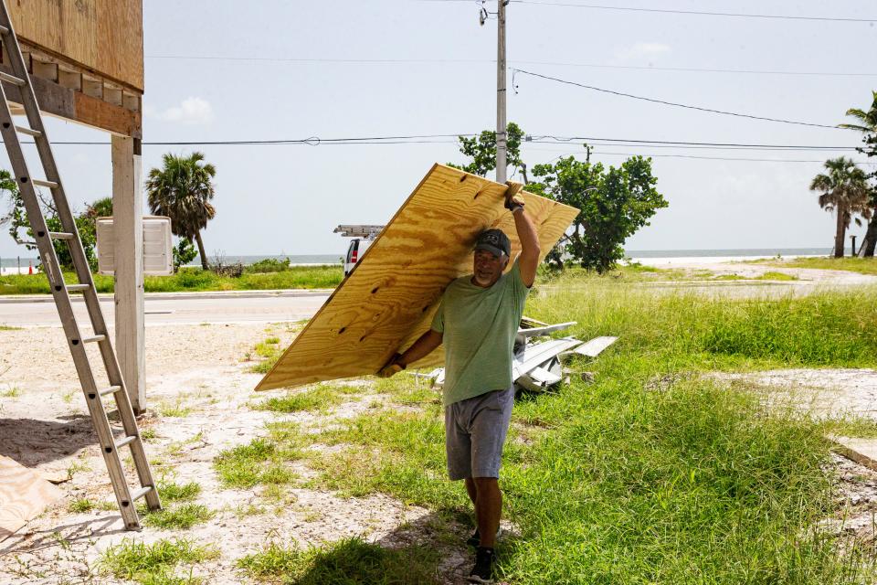 Rick Borman transports sheets of plywood on a hot afternoon on Fort Myers Beach on July, 24, 2023. He was repairing his Hurricane Ian damaged home.