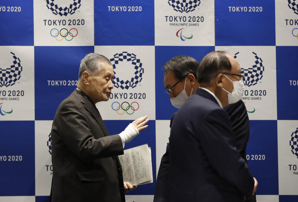 Tokyo Olympic President Yoshiro Mori, left, talks with other board members wearing protective face masks upon arrival at the Tokyo 2020 Executive Board Meeting in Tokyo, Japan Monday, March 30, 2020. President Mori said Monday he expects to talk with IOC President Thomas Bach this week about rescheduling the games for next year. (Issei Kato/Pool Photo via AP)