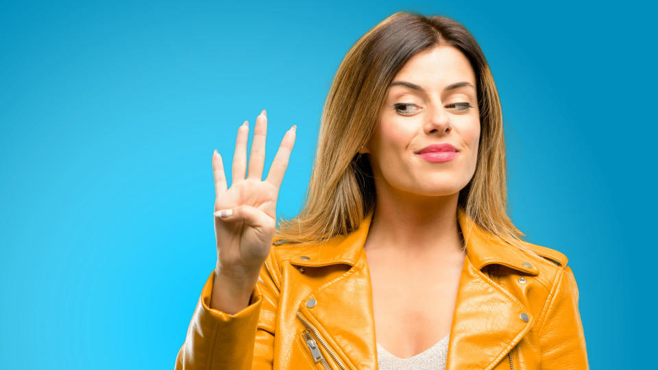 Beautiful young woman raising his finger, is the number four, blue background - Image.