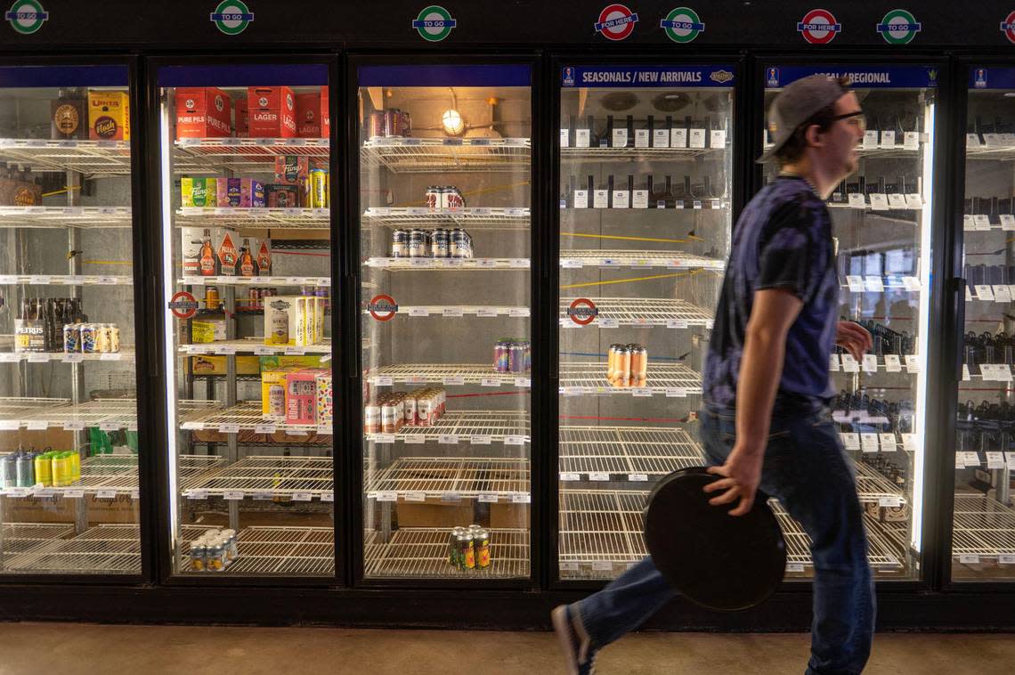 Server Dorian Burton walks by empty coolers at Bier Station on Saturday.