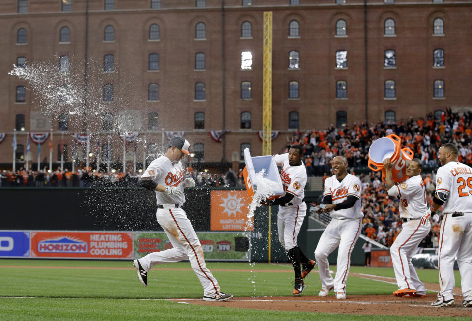 Baltimore Orioles' Mark Trumbo, left, is hit with ice water by teammates Adam Jones, Jonathan Schoop, Manny Machado and Welington Castillo as he runs toward home plate after hitting a solo home run in the 11th inning of an opening day baseball game against the Toronto Blue Jays in Baltimore, Monday, April 3, 2017. Baltimore won 3-2 in 11 innings. (AP Photo/Patrick Semansky)