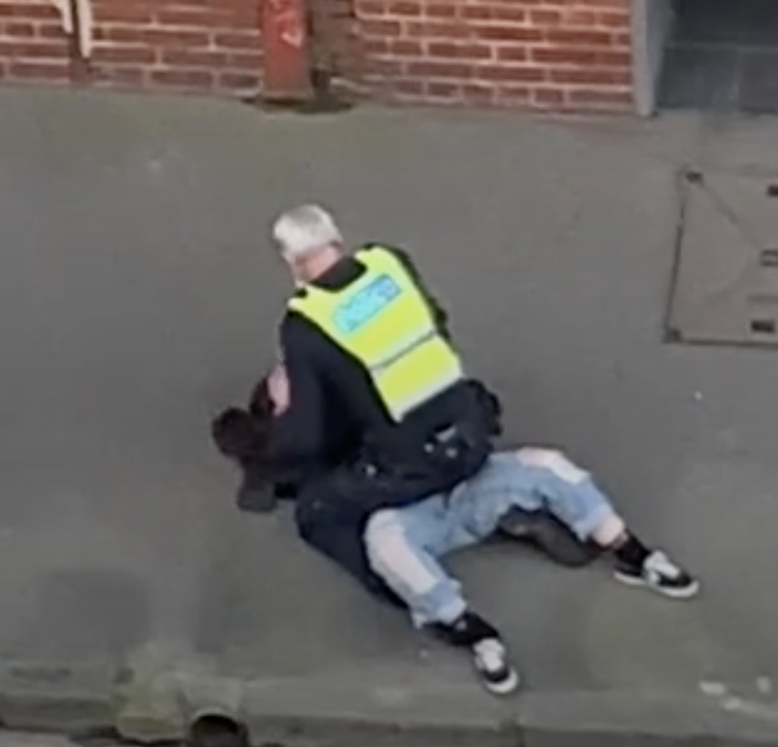 Photo shows a police officer sitting on top of a woman in Melbourne.