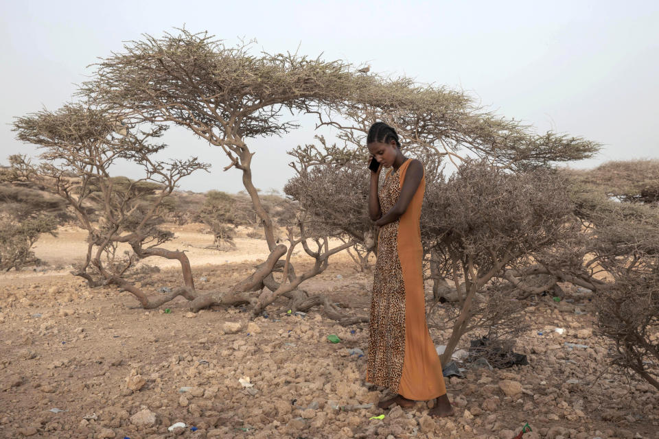 FILE - In this July 15, 2019 file photo, an Ethiopian Tigray migrant, makes a phone call to her mother in Ethiopia, as she takes shelter under trees at the last stop of her journey before leaving by boat to Yemen in the evening, in Obock, Djibouti. Ethiopia's Tigray region was among the leading sources of new flows of refugees and internally displaced people in 2020, according to Global Trends report released on Friday June 18, 2021, by the United Nations refugee agency UNHCR. (AP Photo/Nariman El-Mofty, FILE)