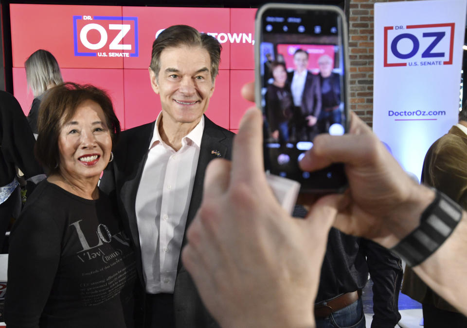 Mehmet Oz, the TV celebrity and heart surgeon who is running for the Republican nomination for U.S. Senate in Pennsylvania, poses for a photo with an attendee after he spoke at a town hall-style event at the Newtown Athletic Club, Feb. 20, 2022, in Newtown, Pa. (AP Photo/Marc Levy)