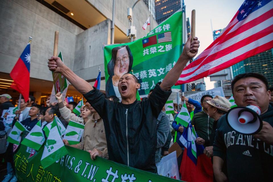 A protester shouts in front of a banner with a picture of Taiwanese President Tsai Ing-wen.