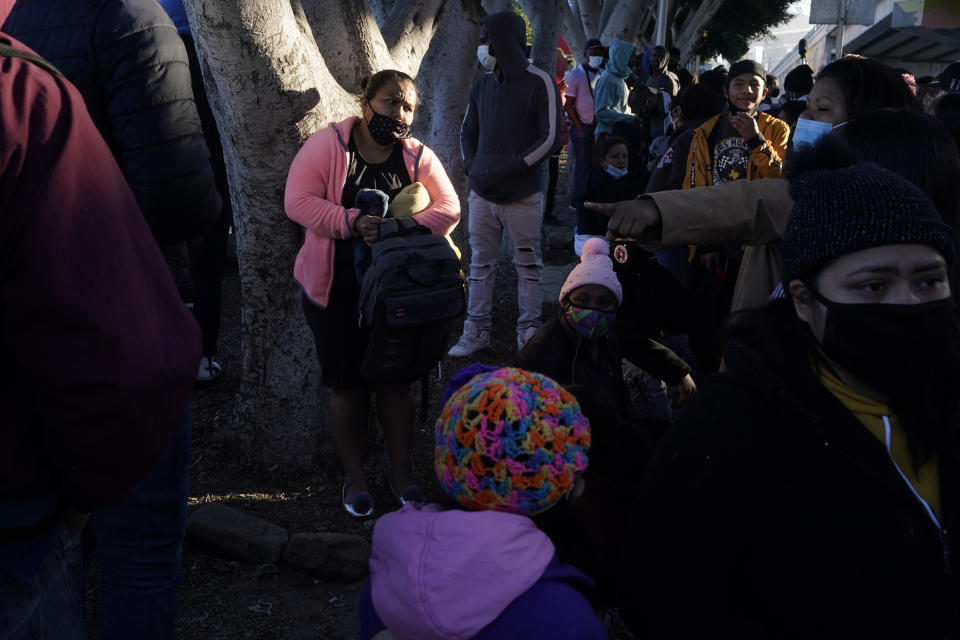 FILE - A woman seeking asylum in the United States waits with others for news of policy changes on Feb. 19, 2021, in Tijuana, Mexico. The Biden administration is set to reinstate a Trump-era policy to make asylum-seekers wait in Mexico for hearings in U.S. immigration court this week with changes and additions. A U.S. official says the first migrants are to be sent from El Paso, Texas, back to Ciudad Juarez. Timing was in flux as officials made final preparations but it may begin Tuesday, Dec. 7, 2021. (AP Photo/Gregory Bull, File)