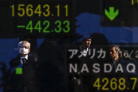 People are reflected in a display showing market indices outside a brokerage in Tokyo, Japan, February 10, 2016. REUTERS/Thomas Peter