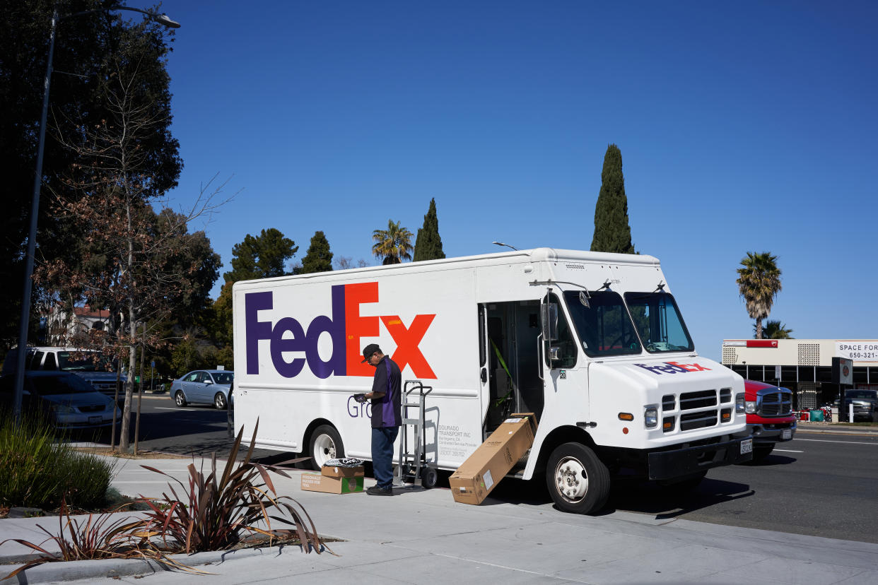 Mountain View, CA, USA - Mar 3, 2020: FedEx delivery driver unloads his truck and sorts packages by the roadside in Mountain View, California, United States.