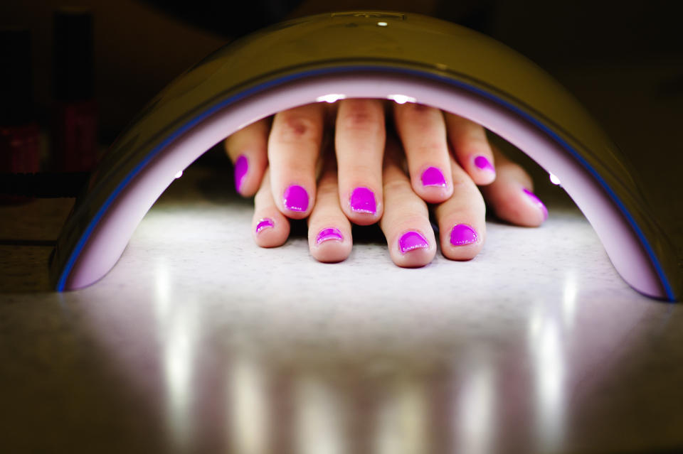 hand inside lamp for nails on table close up. UV lamp for drying nails with gel method. violet nails dried in the lamp