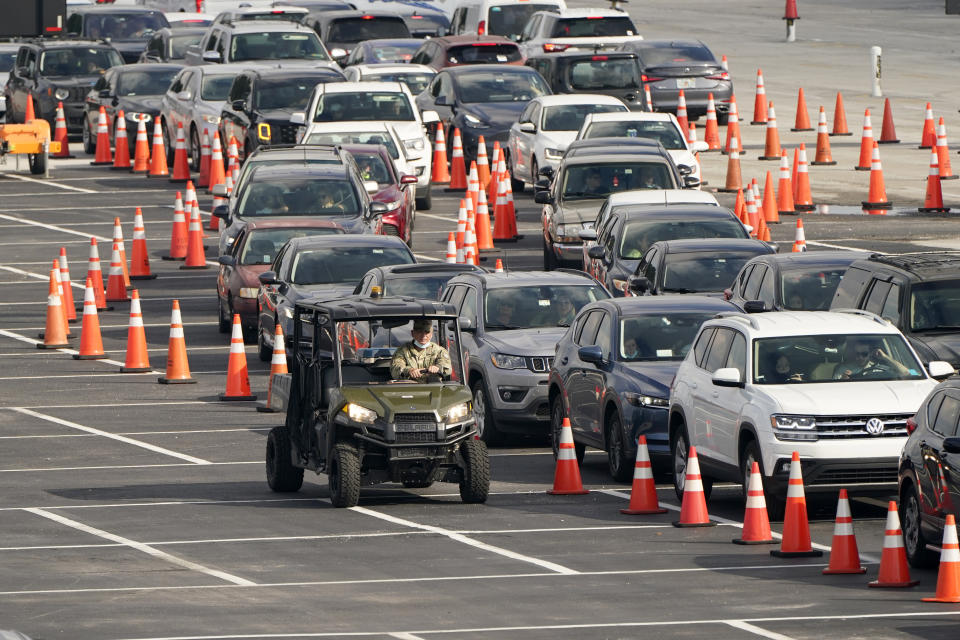 FILE - In this Nov. 23, 2020, file photo, vehicles wait in line at a COVID-19 testing site at Hard Rock Stadium in Miami. After a punishing fall that left hospital struggling, some Midwestern states are seeing a decline in new coronavirus cases. But the signs of improvement are offset by the infection's accelerating spread on both coasts. (AP Photo/Lynne Sladky, File)