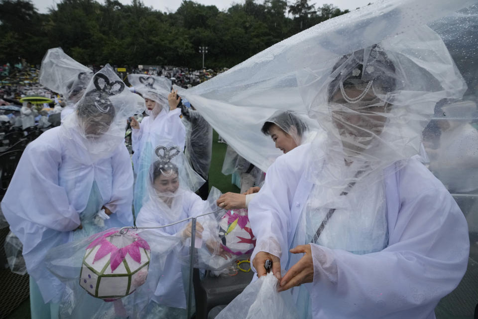 Buddhists cover themselves and their lamps with plastic sheets as they prepare for a lantern parade ahead of the upcoming birthday of Buddha at Dongguk University in Seoul, South Korea, Saturday, May 11, 2024. (AP Photo/Ahn Young-joon)