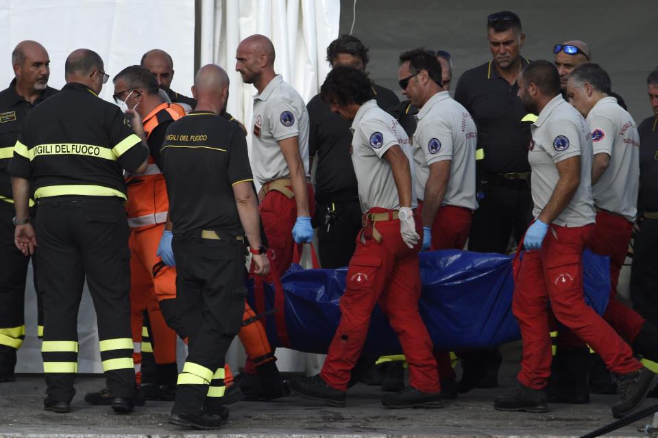 Italian Firefighters scuba divers bring ashore in a blue bag the body of one of the victims of the UK flag vessel Bayesian, Wednesday, Aug. 21, 2024. The sail yacht was hit by a violent sudden storm and sunk early Monday, while at anchor off the Sicilian village of Porticello near Palermo, in southern Italy. (AP Photo/Salvatore Cavalli)