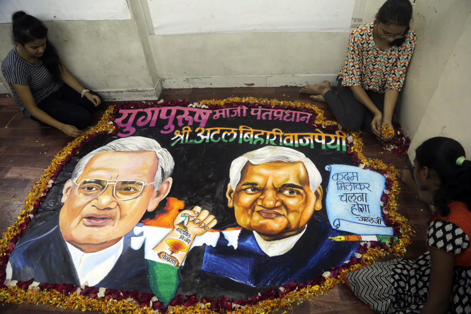 Students from an art school place flower petals around a painting of former Indian prime minister Atal Bihari Vajpayee in Mumbai, India, Thursday, Aug. 16, 2018. Vajpayee, who pursued both nuclear weapons and peace talks with Pakistan, died Thursday at age 93. (AP Photo/Rajanish Kakade)