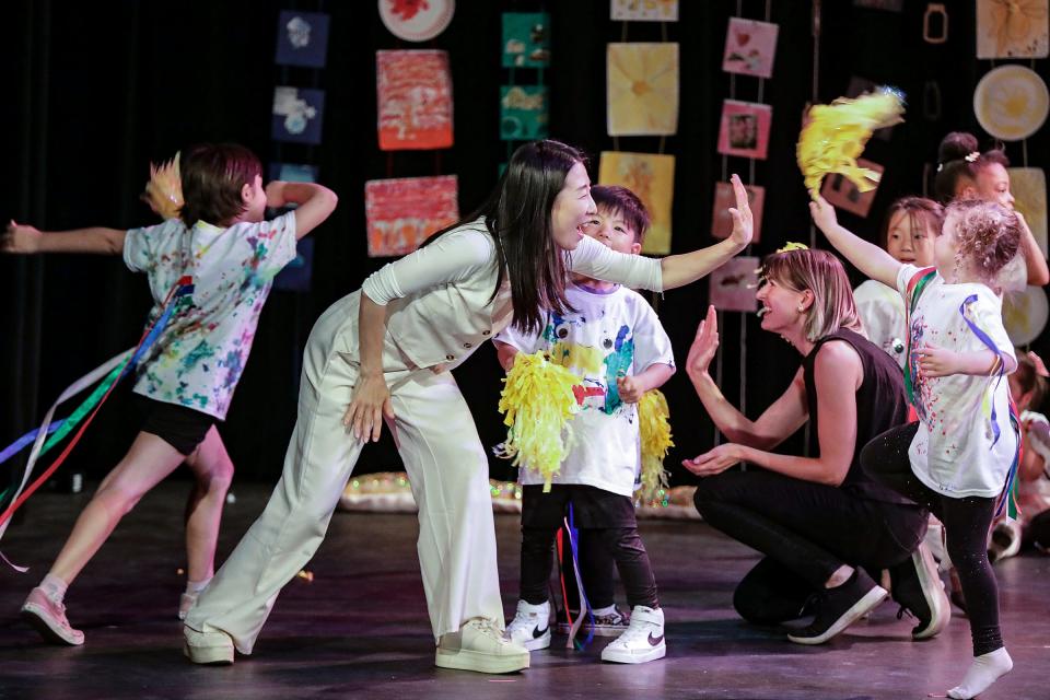 Joori Jung, 40, of Troy, gives students high-fives during the Creative Thinkers and Movers performance during the Artlab J dance recital at Marygrove Theatre in Detroit on June 9, 2023.