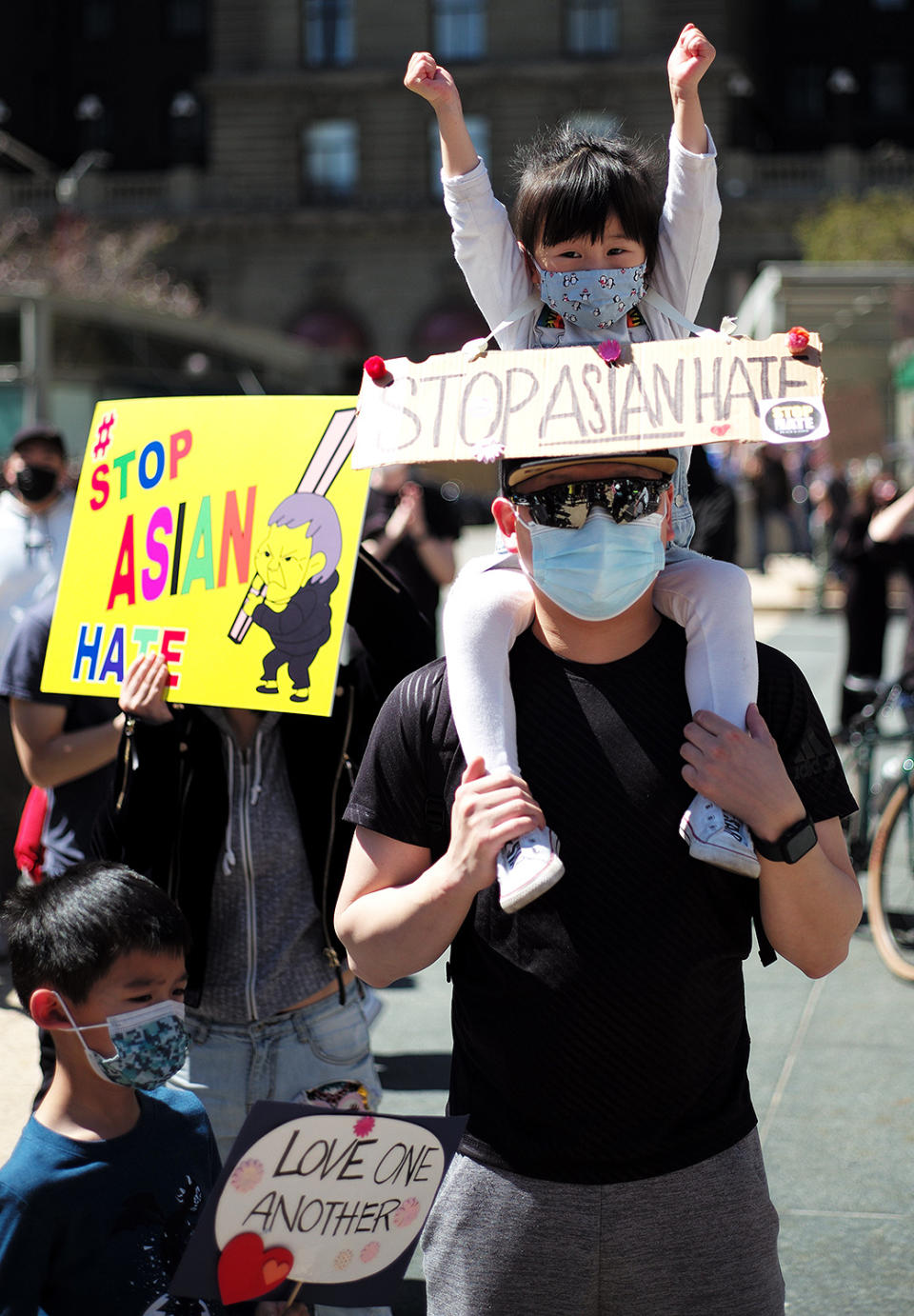 <p>A young girl raises her fists while wearing a "Stop Asian Hate" sign around her neck as many gathered at Union Square in San Francisco on March 27.</p>