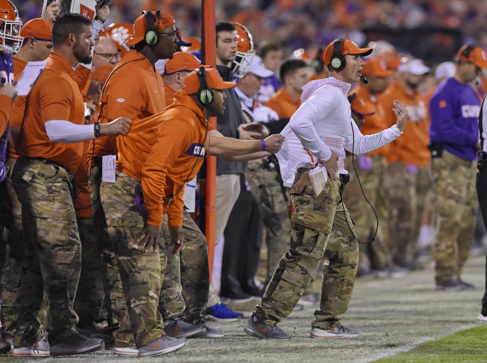 Clemson defensive coach Brent Venables (R) is pulled back by an assistant during the first half of a college football game. (AP)