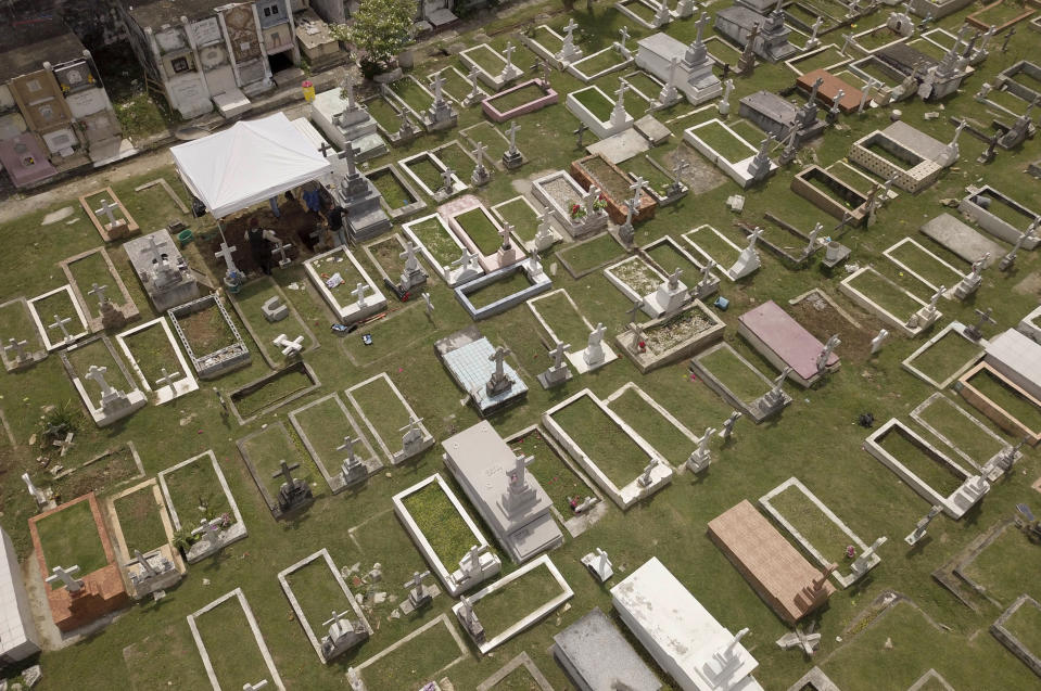 People gather under a tent as they exhume the body of Julius H. Kroehl from Amador Cemetery in the Chorrillo neighborhood of Panama City, Thursday, Oct. 11, 2018. The remains of Kroehl, a German-American who was a pioneer on the design of the first submarine to submerge successfully at depth, are being moved to Corozal Cemetery where American veterans are buried. (AP Photo/Arnulfo Franco)