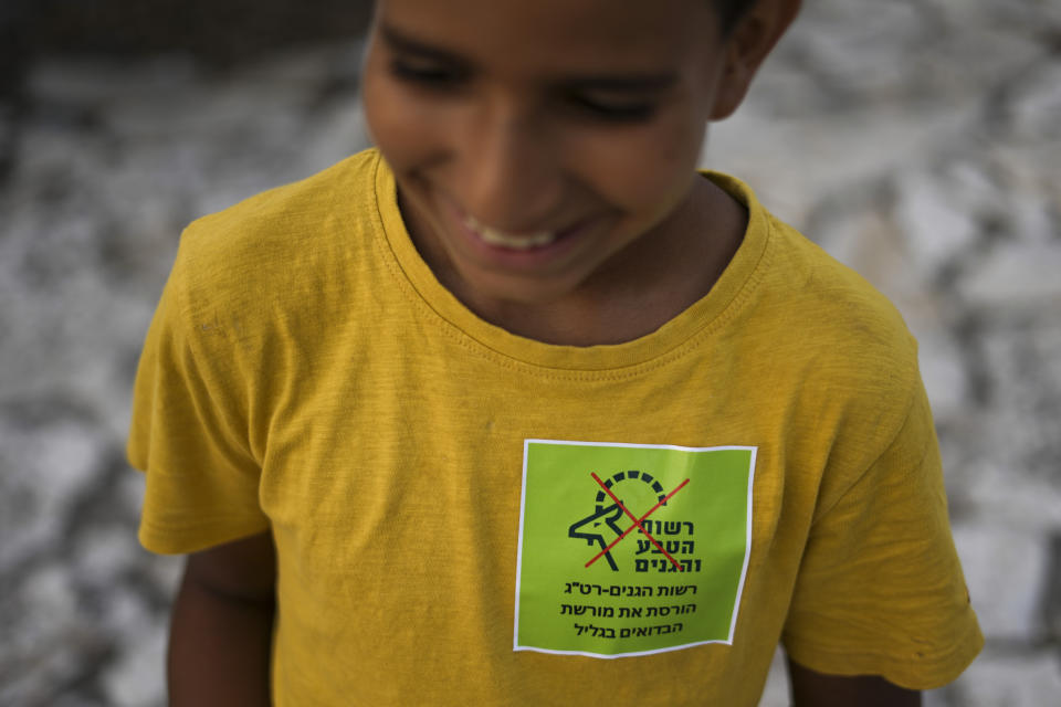An Israel Arab Beduin boy has a sticker that say "National Parks Authority ruins the Beduins legacy in the Galilee " during protest in Zubaydat, Israel, Wednesday, Aug. 31, 2022. A new plan to turn the 2,500-acre area into a wildlife corridor that has sparked rare protest from Bedouin in the northern Galilee region who were one of the few Palestinians to embrace early Zionist pioneers before 1948, and since served in the police and military often fighting against fellow Palestinians, Jordanians, Egyptians and Syrians. (AP Photo/Ariel Schalit)