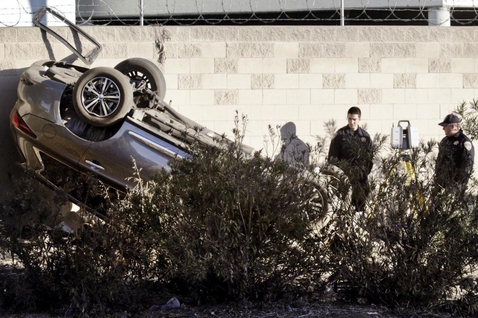 Police stand by an overturned vehicle.