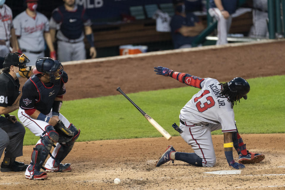 Atlanta Braves' Ronald Acuna Jr. drops to the ground next to Washington Nationals catcher Yan Gomes after fouling the ball off his left foot during the fourth inning of a baseball game in Washington, Friday, Sept. 11, 2020. Acuna was helped off the field. (AP Photo/Manuel Balce Ceneta)