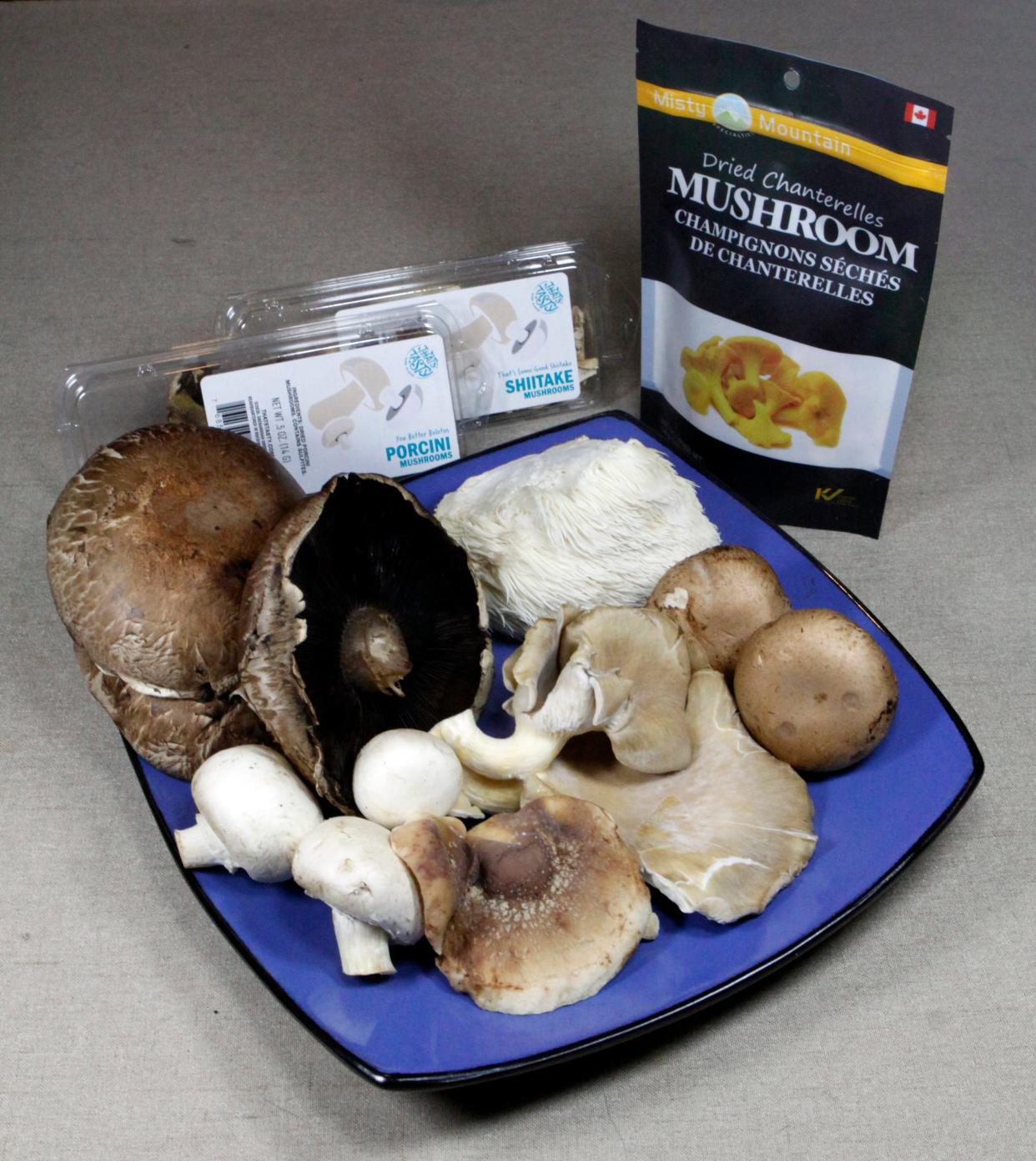 Edible mushrooms come in many varieties. On the plate, clockwise from top left, are fresh portobello caps, lion's mane, baby portobello, oyster, shiitake and white button mushrooms. Packaged in the back are dried porcini, shiitake and chanterelle mushrooms.