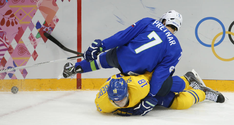 Slovenia defenseman Klemen Pretnar (7) falls on top of Sweden forward Jakob Silfverberg in the second period of a men's ice hockey game at the 2014 Winter Olympics, Wednesday, Feb. 19, 2014, in Sochi, Russia. (AP Photo/Mark Humphrey)