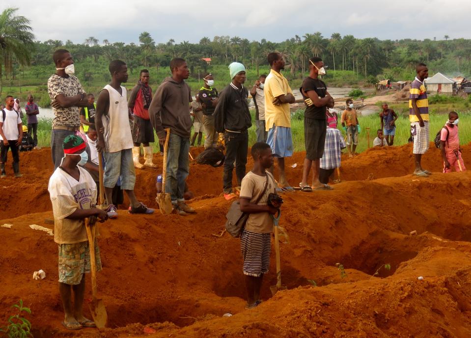 <p>Men wait beside empty graves for the coffins of mudslide victims on Aug. 17, 2017 at Waterloo cemetery near Freetown, Sierra Leone. (Photo: Stringer/Anadolu Agency/Getty Images) </p>