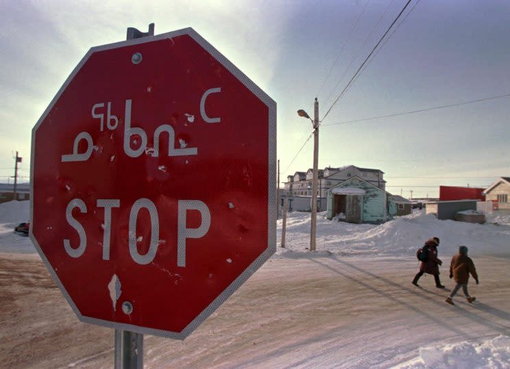 A stop sign written in both English and the traditional Inuit language of Inuktitut is seen in the eastern Arctic community of Iqaluit, NWT, Photo from The Canadian Press