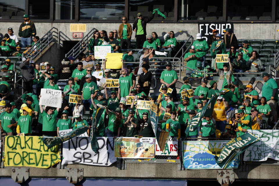 FILE - Fans hold signs at Oakland Coliseum to protest the Oakland Athletics' planned move to Las Vegas, before a baseball game between the Athletics and the Tampa Bay Rays in Oakland, Calif., Tuesday, June 13, 2023. (AP Photo/Jed Jacobsohn, File)