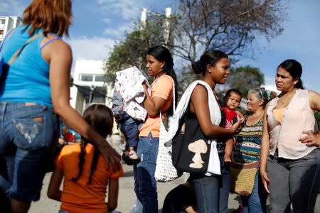 Women carrying babies queue next to others to try to buy food and staple items outside a supermarket in Caracas May 17, 2016. REUTERS/Carlos Garcia Rawlins