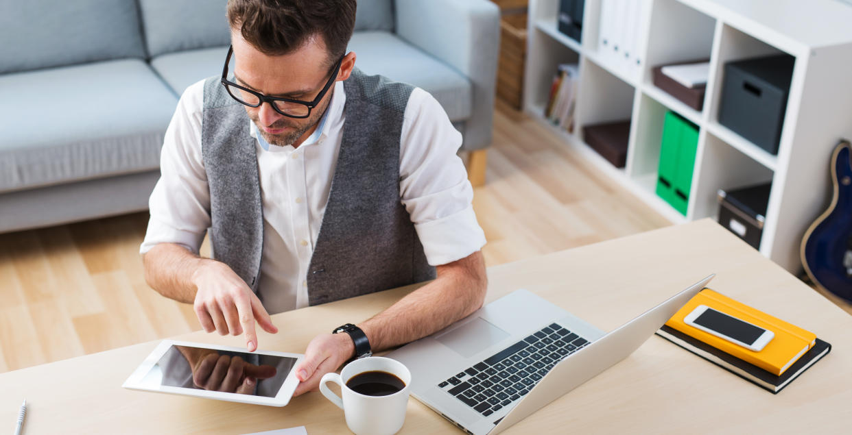 man at home desk on tablet and laptop