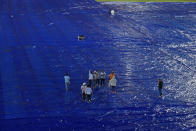Groundsmen stand on the rain covers as the Indian Premier League cricket match between Gujrat Titans and Sunrisers Hyderabad is delayed due to rain in Hyderabad, India, Thursday, May 16, 2024. (AP Photo /Mahesh Kumar A.)