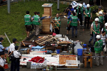 Policemen look on as workers from the Lands Department remove encampments outside government headquarters in Hong Kong, China June 24, 2015. REUTERS/Bobby Yip