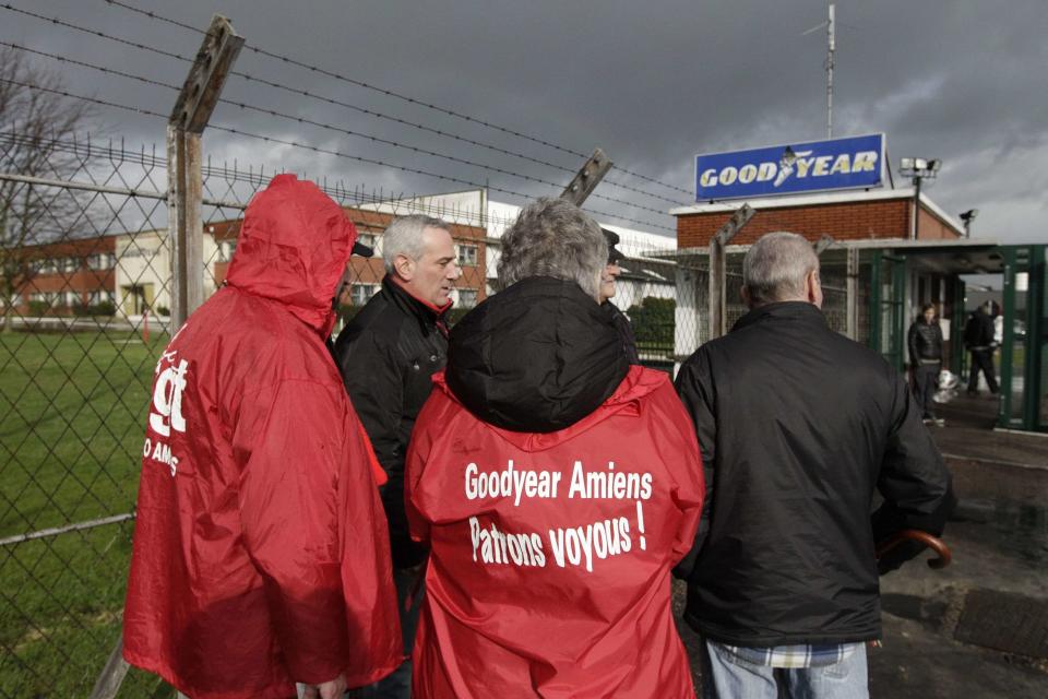 Labour union members stand at the entrance of the Goodyear tyres factory in Amiens, northern France, in this January 31, 2013 file picture. French trade unionists held two executives overnight on Tuesday January 7, 2014 at the country's Goodyear tyre plant - a flashpoint for France's troubled industrial relations - to demand higher pay-outs for more than a thousand planned layoffs. Workers at the idled factory in the northern city of Amiens have been trying to negotiate redundancy terms with management for nearly a year, after Texan tyre tycoon Maurice Taylor withdrew a potential rescue bid on the grounds that French workers were lazy - triggering a political storm. The message reads "Goodyear - Gangster Bosses". Picture taken January 31, 2013. REUTERS/Pascal Rossignol/Files (FRANCE - Tags: BUSINESS EMPLOYMENT)